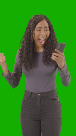 Vertical-Video-Woman-Looking-At-Mobile-Phone-And-Celebrating-Good-News-Against-Green-Screen-4